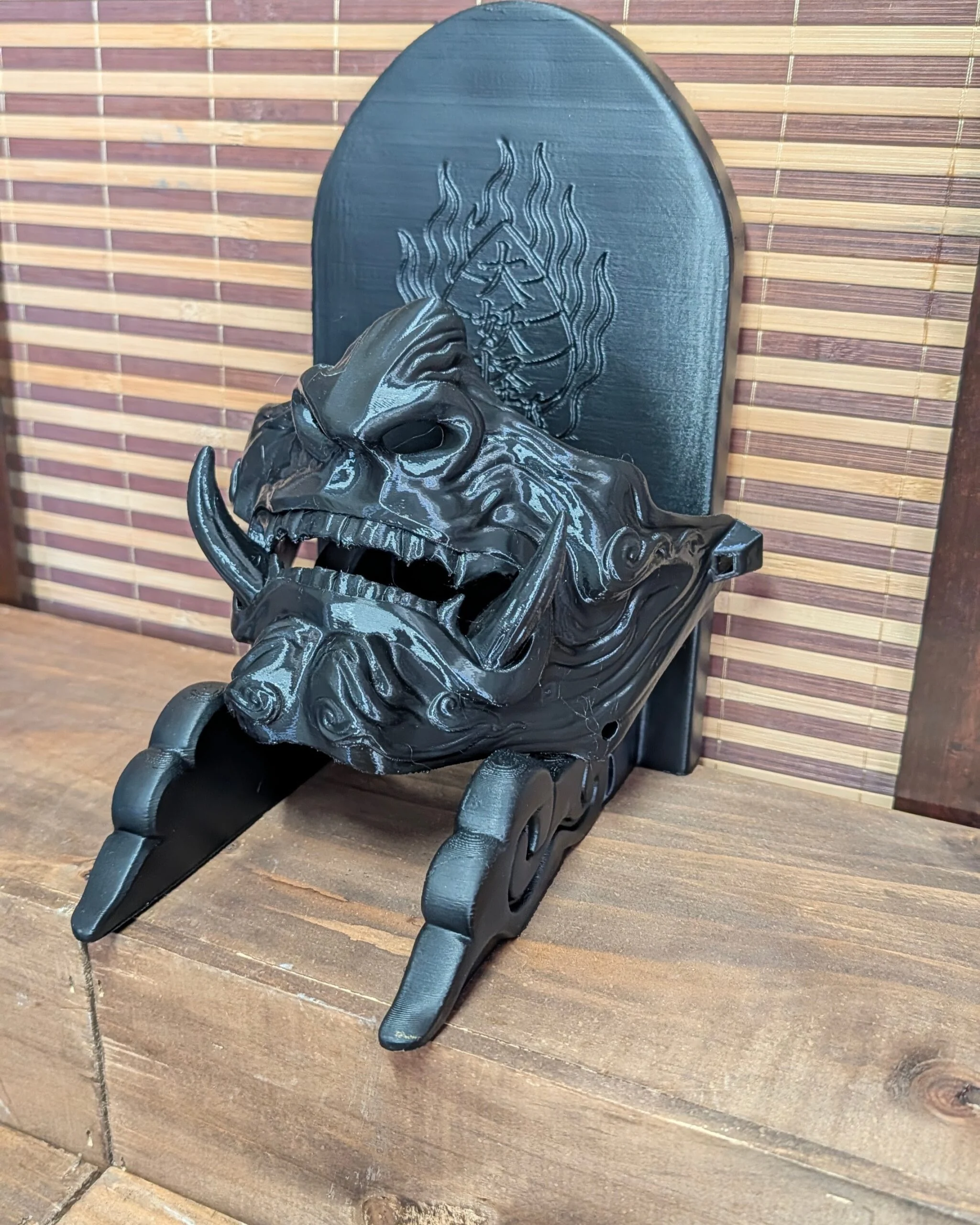 Demi-masque Mempo Oni noir, posé sur étagère