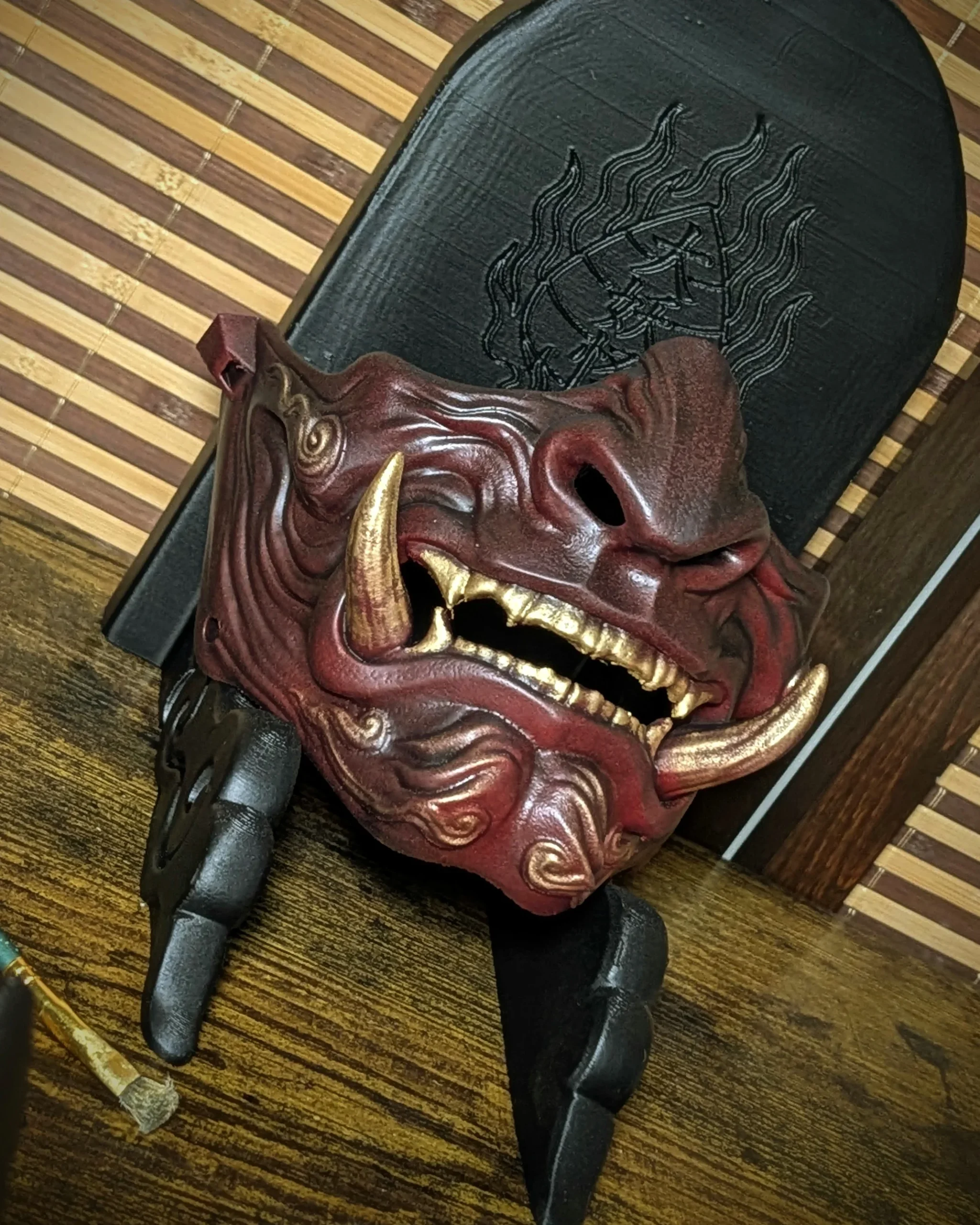 Demi-masque Mempo Oni rouge à dents dorées, vue de trois quarts