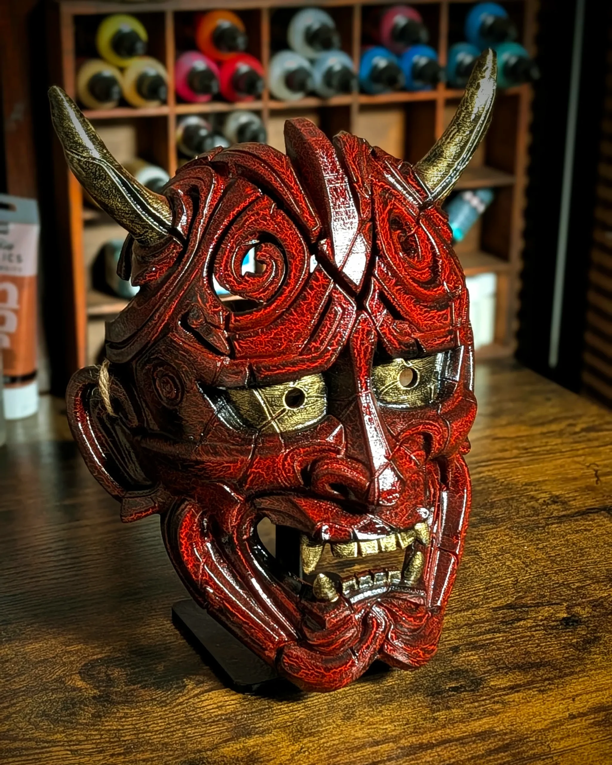 Máscara Hannya Kezurata roja con relieves craquelados y cuernos dorados en el taller Dai Yokai