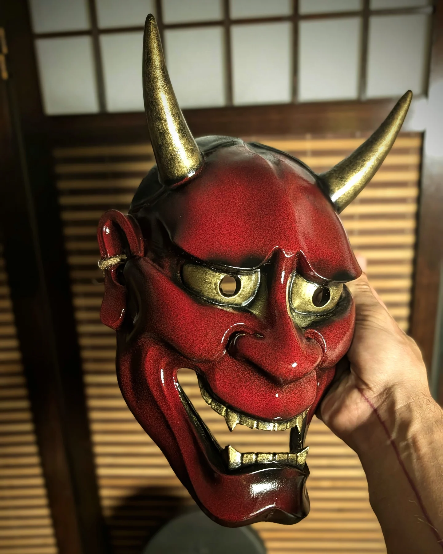Masque Hannya moderne rouge brillant tenu en main, finition vernie