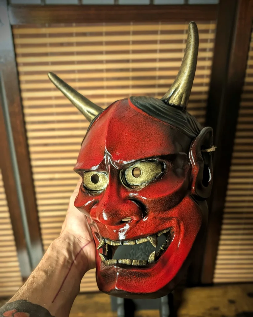 Gros plan d’un masque Hannya rouge sous un éclairage latéral