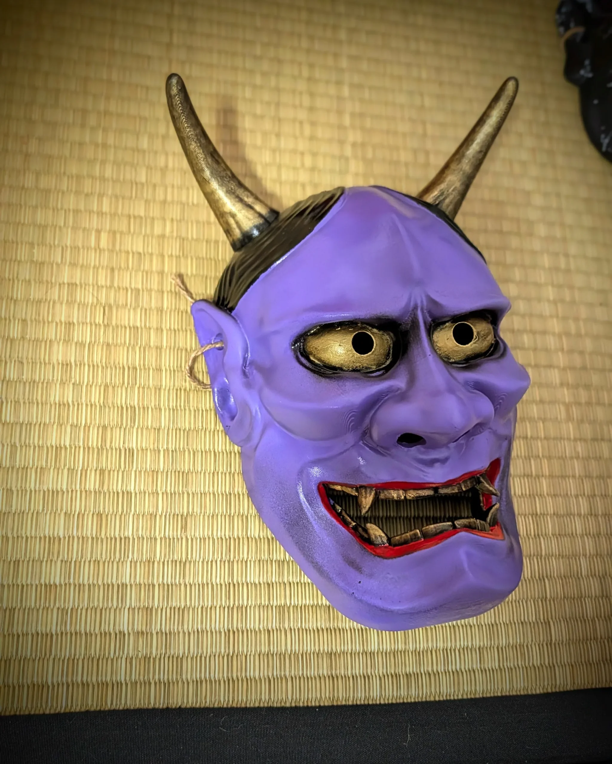 Masque hannya violet vue trois-quarts droite sur tatami mural, cornes dorées, fabriqué en France