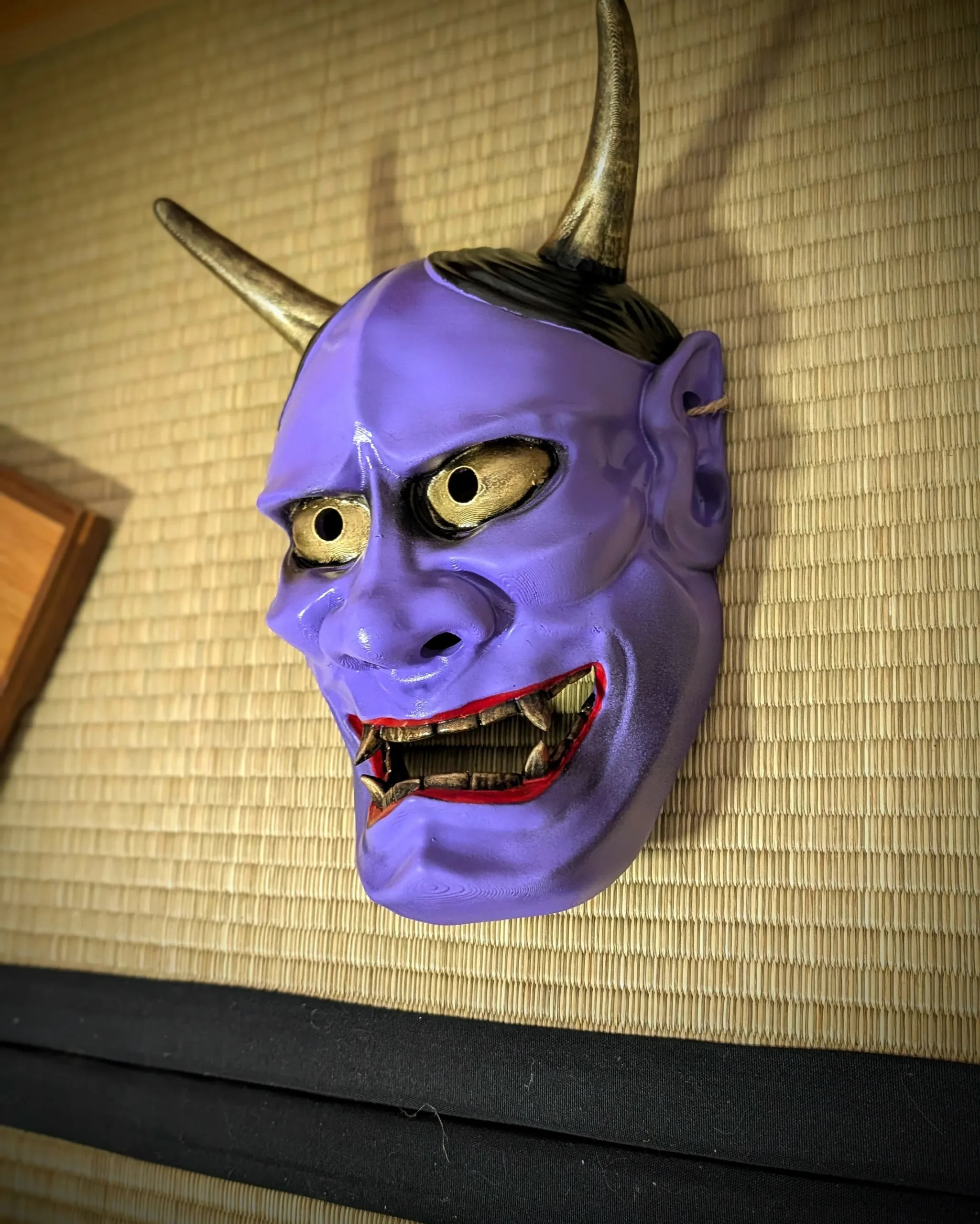 Masque hannya violet accroché sur tatami, vue trois-quarts gauche, yeux dorés, Dai Yokai