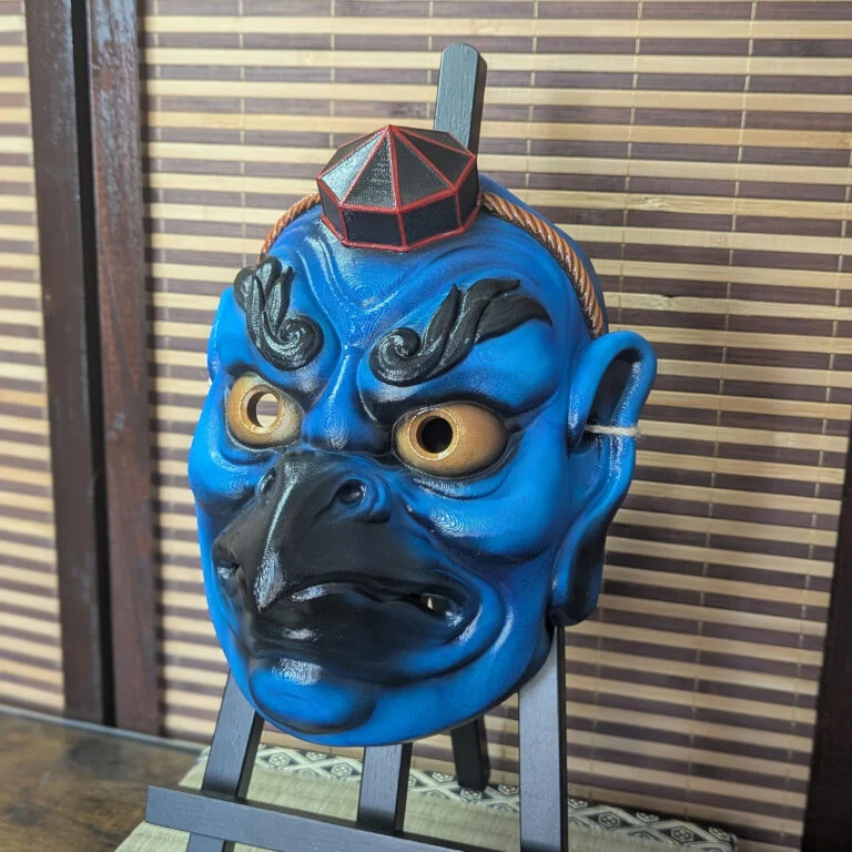 Green Karasu Tengu warrior mask on a display stand, front view