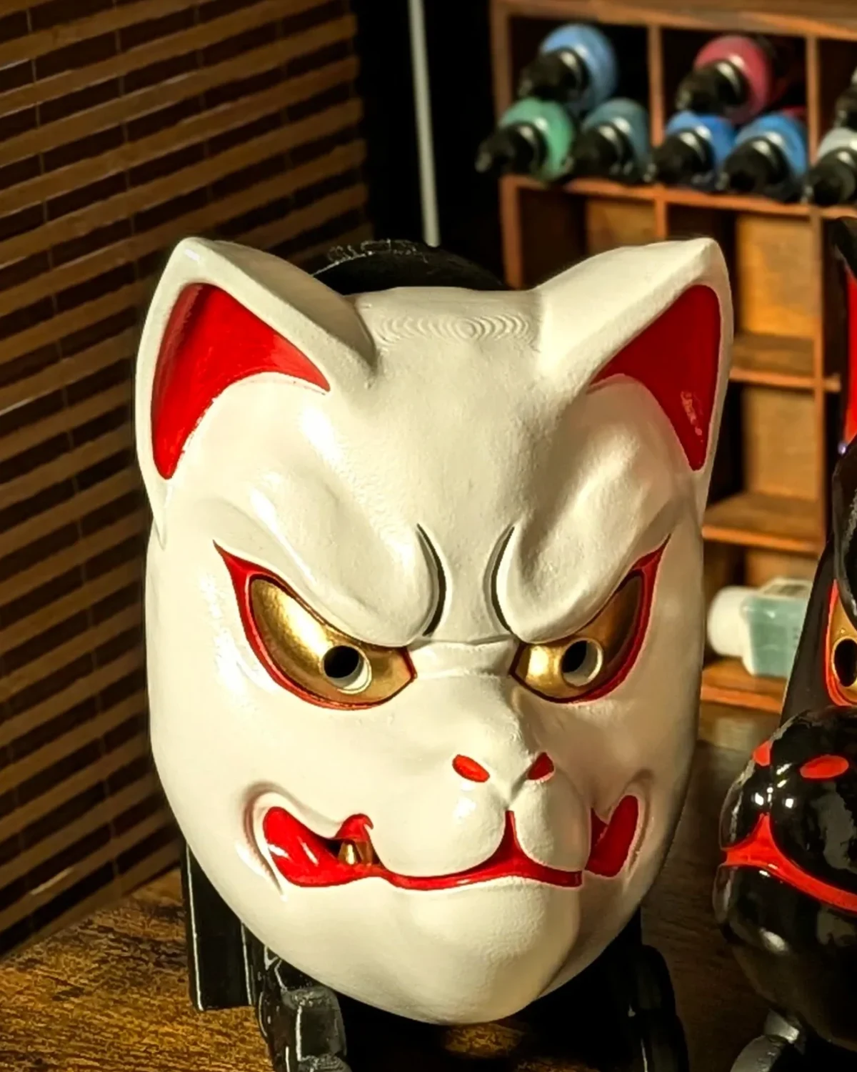 Masque Kitsune blanc traditionnel vu de face, finition blanche avec accents rouges et dorés.