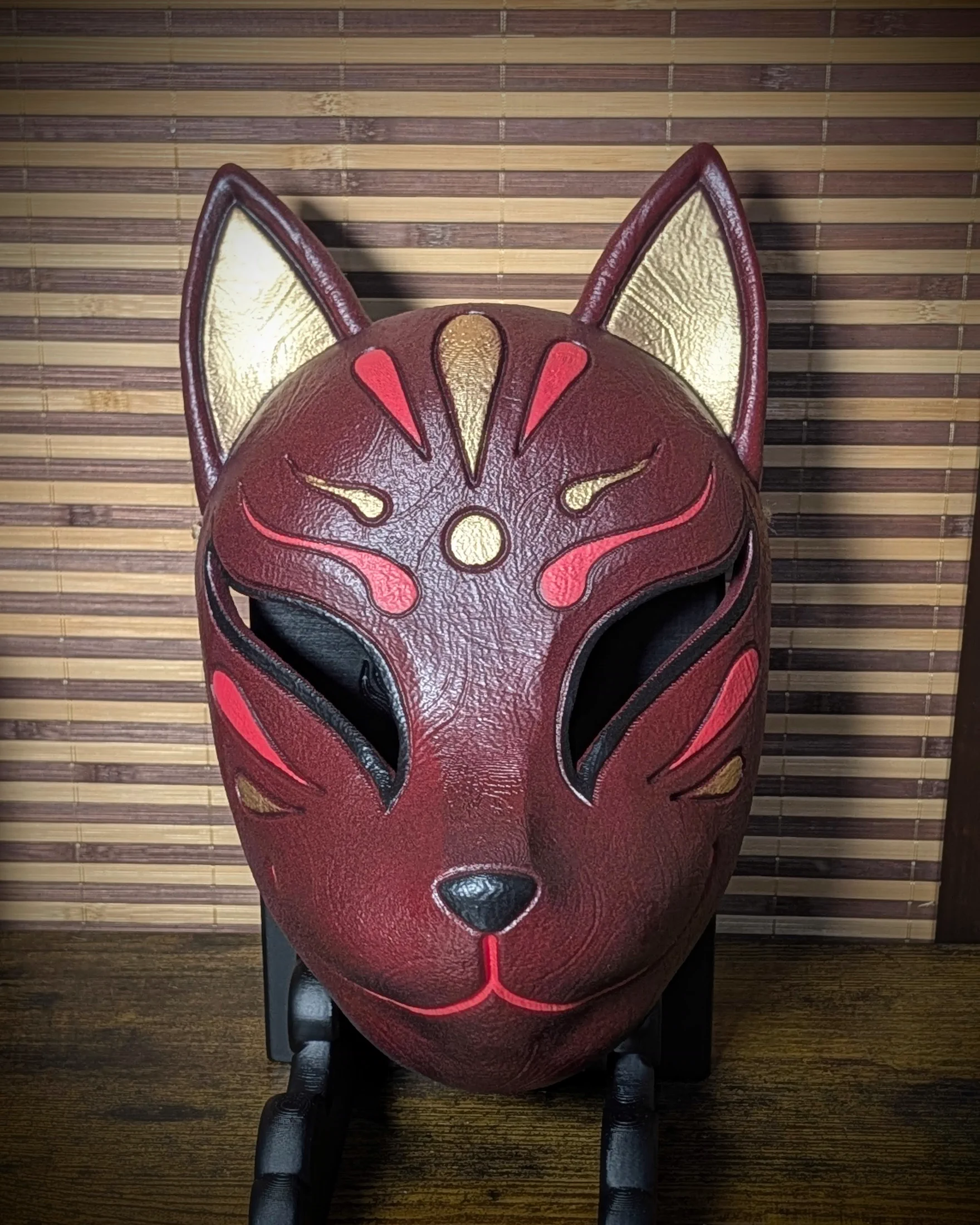 Máscara Kitsune roja vista de frente sobre su soporte