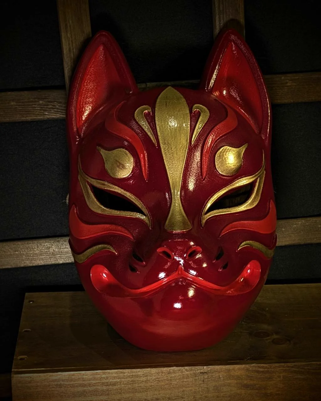 Modern red and gold Kitsune mask on a table, front view