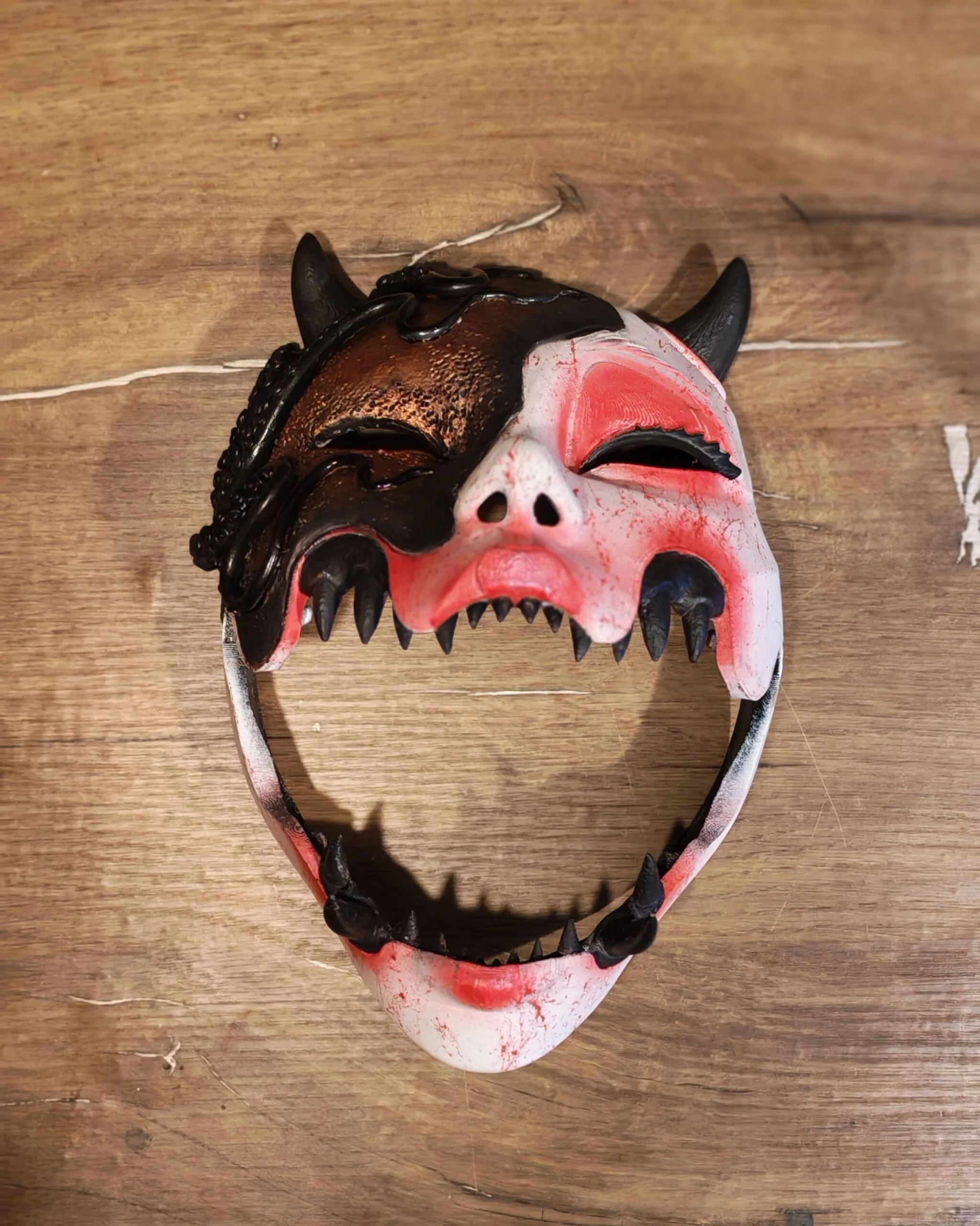 Masque Kuchisake x Adopte ton Poulpe rouge, vue de face du masque articulé posé sur table.