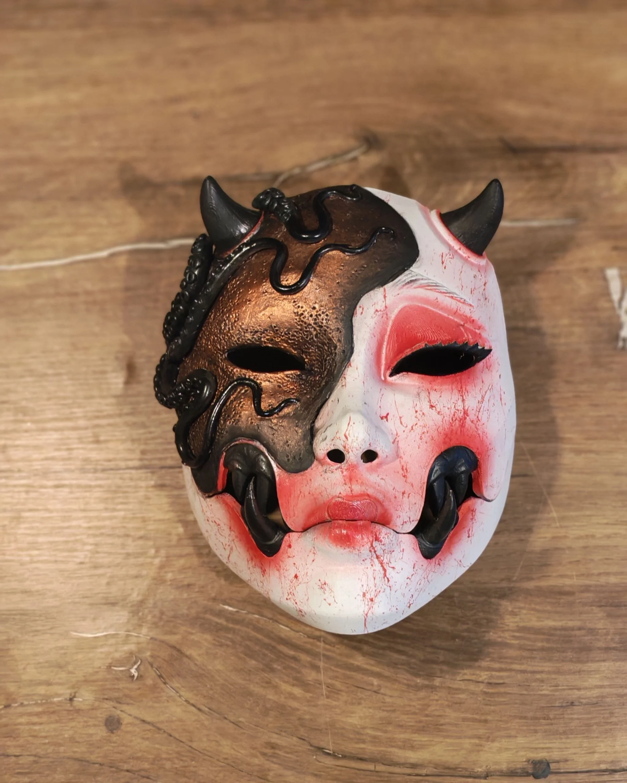 Masque Kuchisake x Adopte ton Poulpe rouge, vue frontale sur table, bouche articulée fermée.