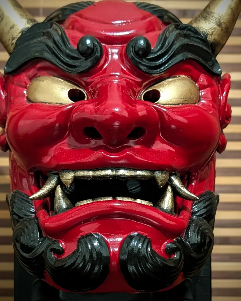 Gros plan masque oni gawara rouge, yeux et dents dorés, travail de peinture acrylique à la main