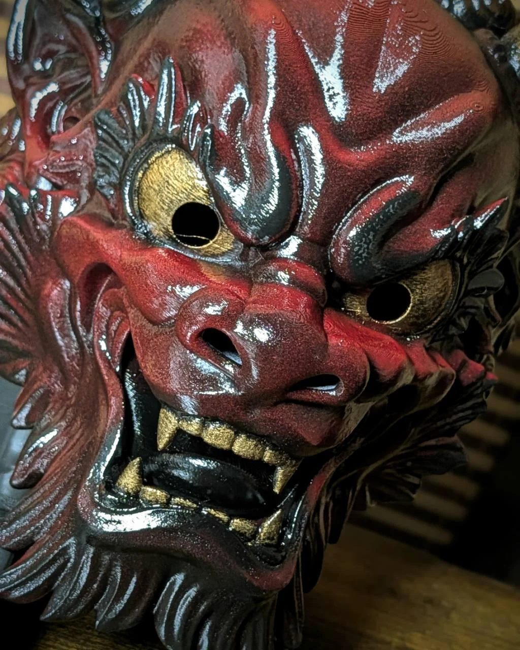 Détail du visage du masque Oni Irezumi bordeaux, finition brillante artisanale