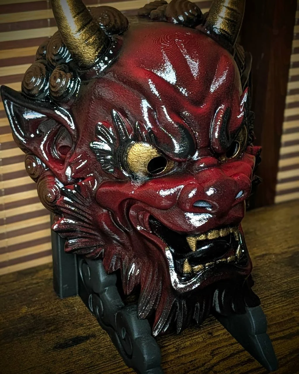 Masque Oni Irezumi bordeaux en vue trois quarts, ombres noires et détails dorés