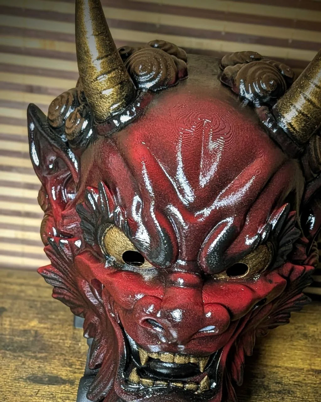 Masque Oni Irezumi bordeaux vu du dessus, cornes dorées et reflets rouges profonds