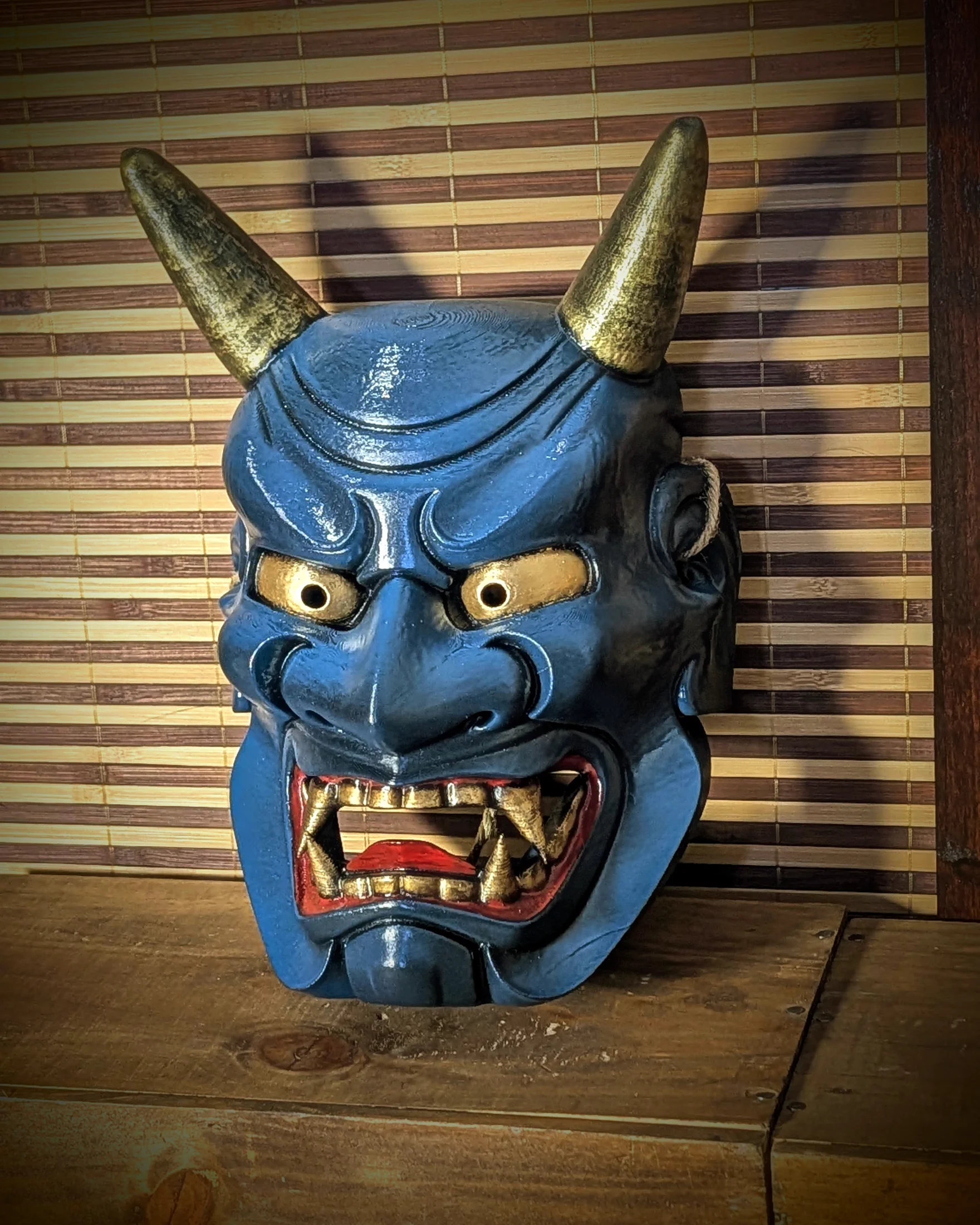 Masque Oni Ondeko bleu vu de trois-quarts sur son support