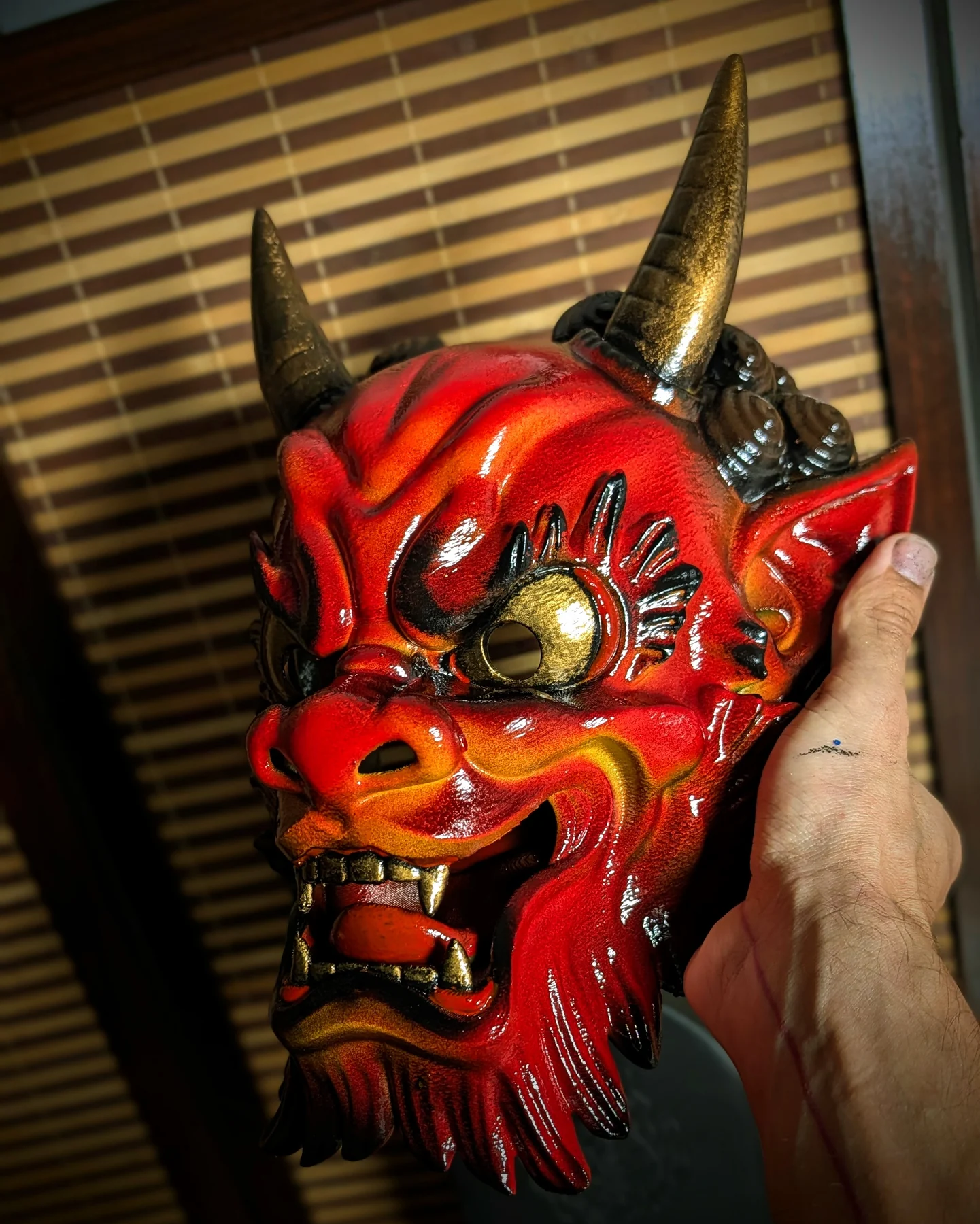 Masque Oni Irezumi rouge en vue trois quarts, détails noirs et dorés peints à la main