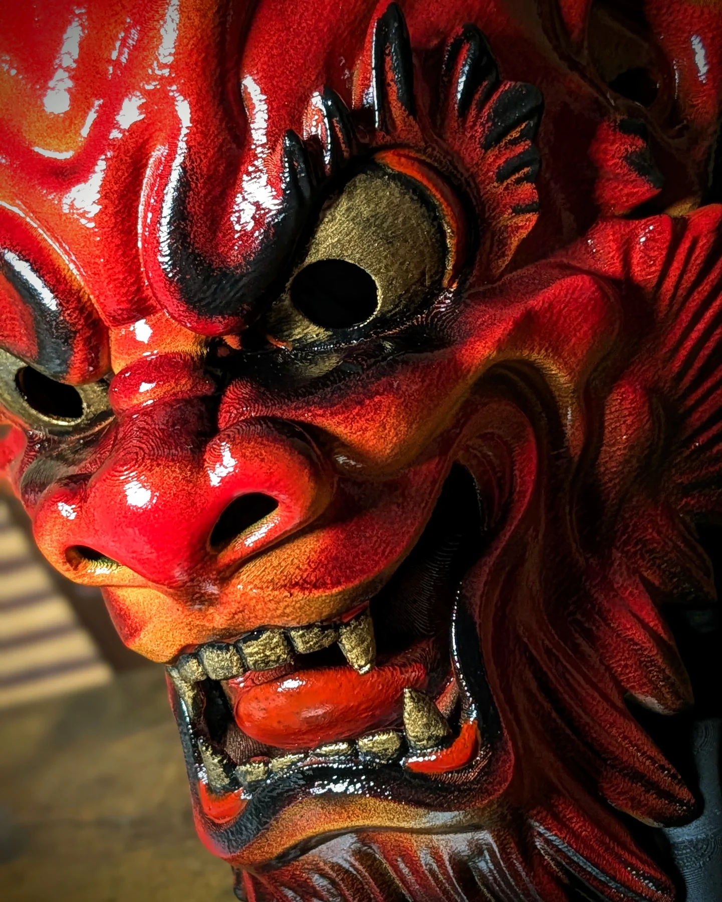 Masque Oni Irezumi rouge tenu en main, taille réelle et finition brillante