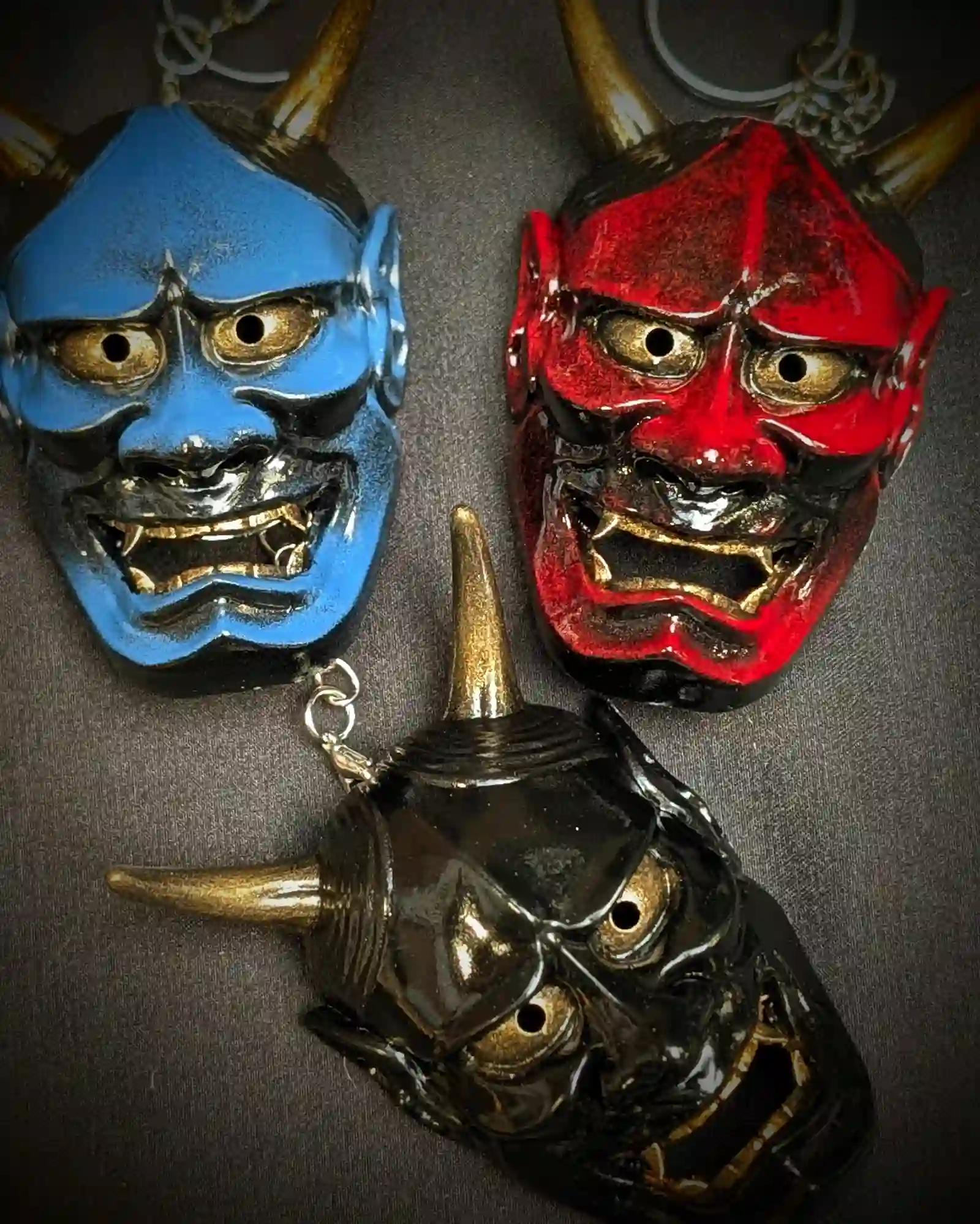 Trois porte-clés Hannya traditionnel rouge bleu et noir accrochés sur support