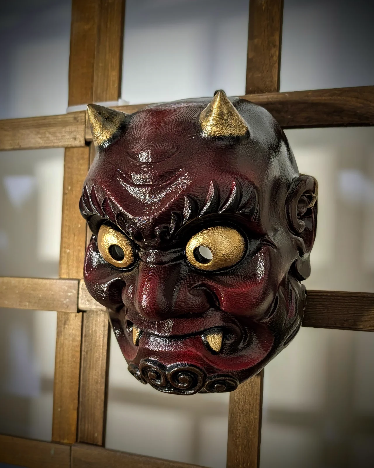 Bordeauxrood en zwart Oni Yabu-masker met gouden hoorns, driekwartaanzicht