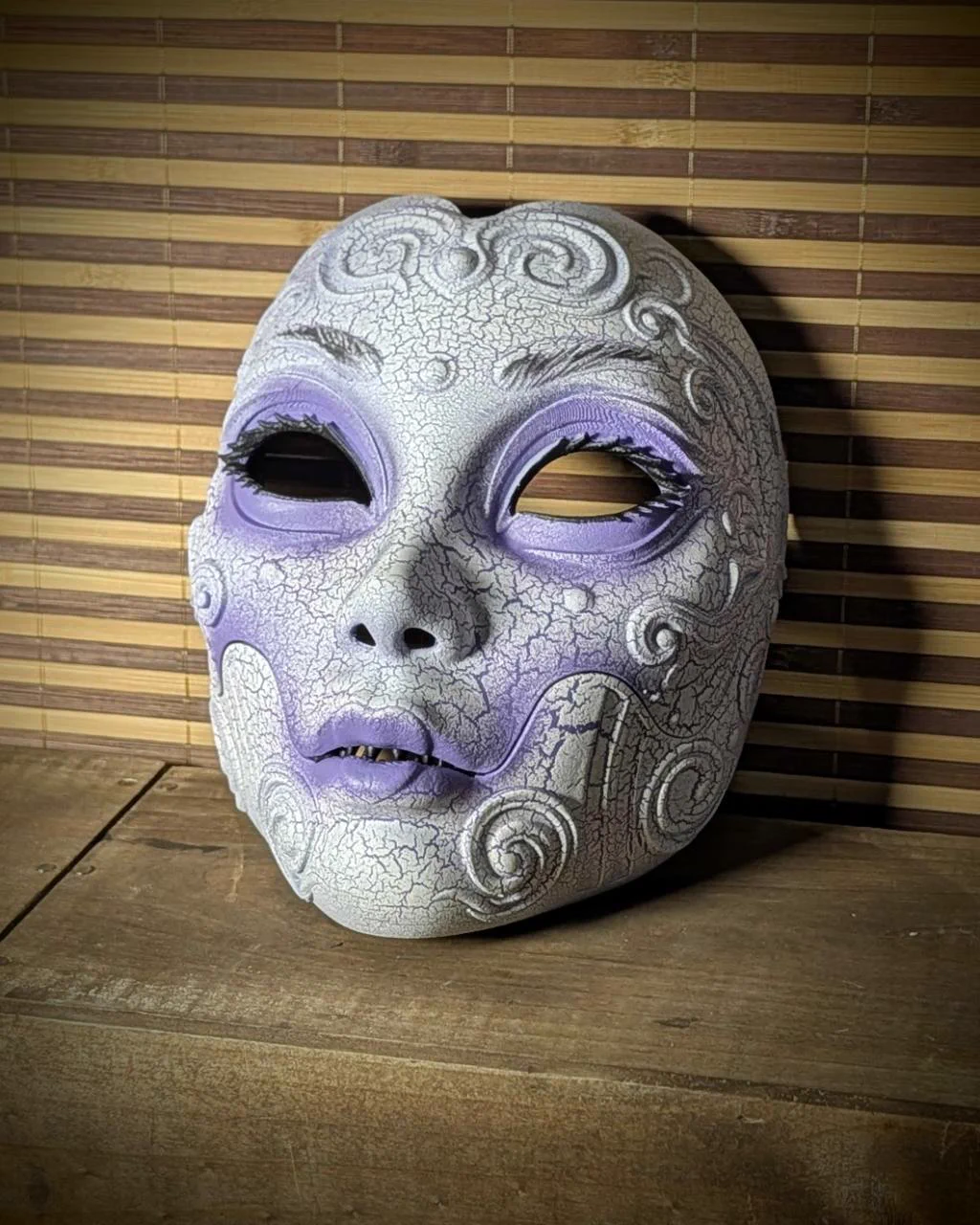 Máscara Geisha Horror blanca craquelada, vista de tres cuartos sobre una mesa