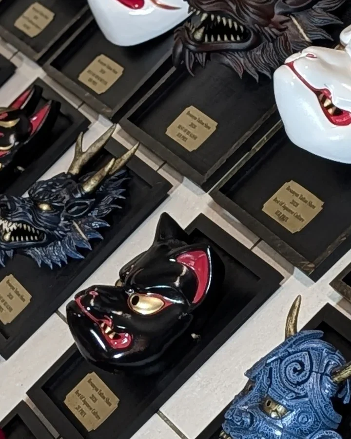 Détail de plusieurs masques-trophées Dai Yokai du BITS 2026, sur cadres noirs avec plaques
