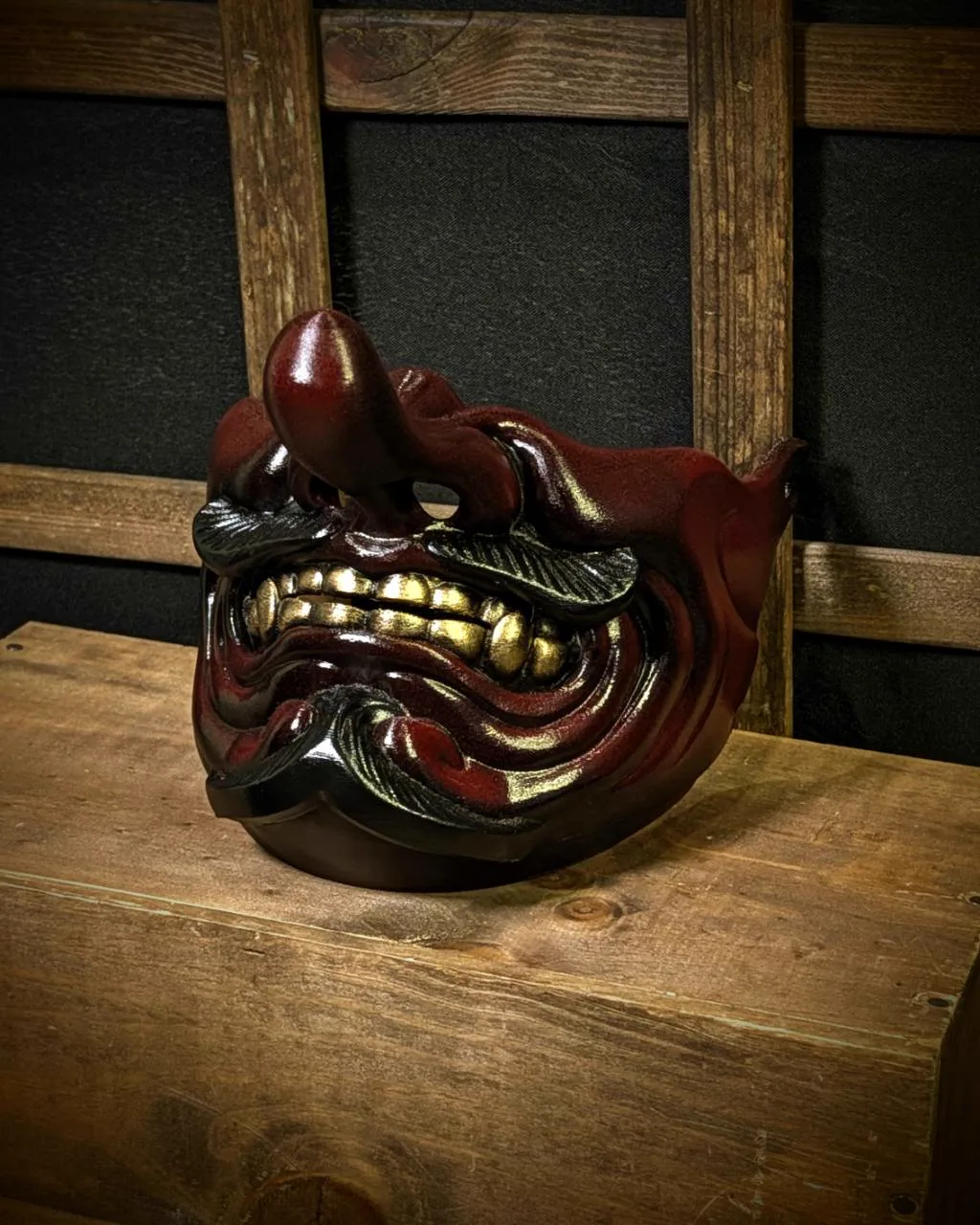 Demi-masque Tengu Kaze rouge et noir avec dents dorées, vue trois-quarts