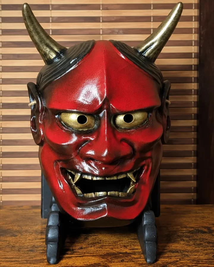 Masque Hannya traditionnel rouge et or présenté sur un support Dai Yokai
