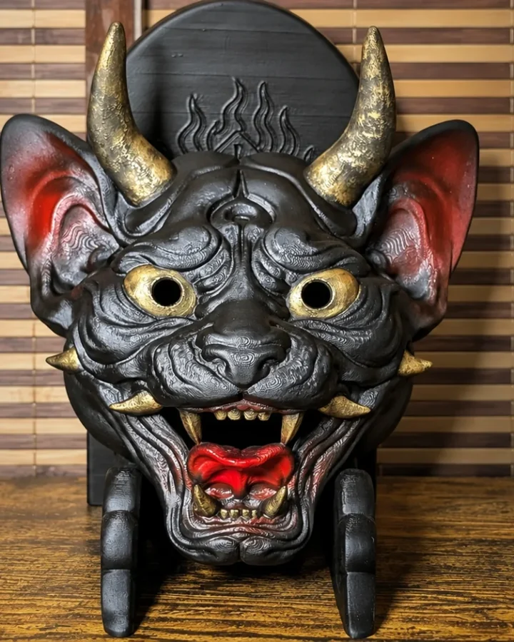 Masque Neko Hannya noir, rouge et or présenté sur un support Dai Yokai