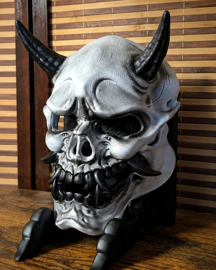 Masque Gashadokuro argenté et noir présenté sur un support Dai Yokai