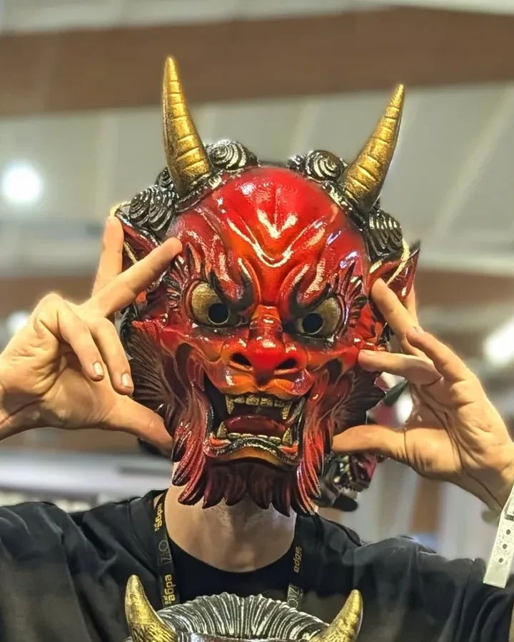 Oni Irezumi rouge feu tenu devant le visage, cornes dorées et mains de chaque côté