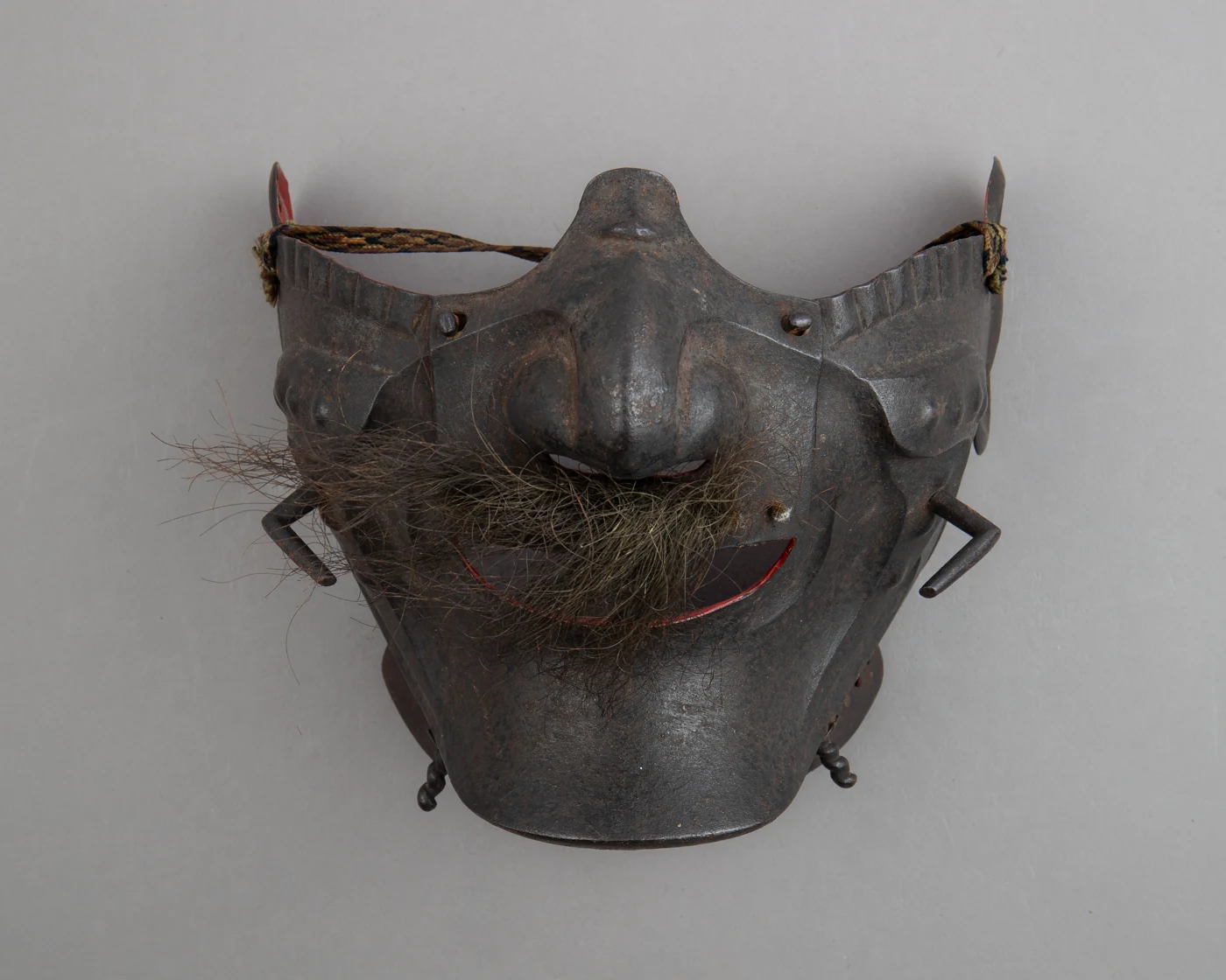 Dark iron menpō with a projecting nose, moustache, mouth opening and side hooks.
