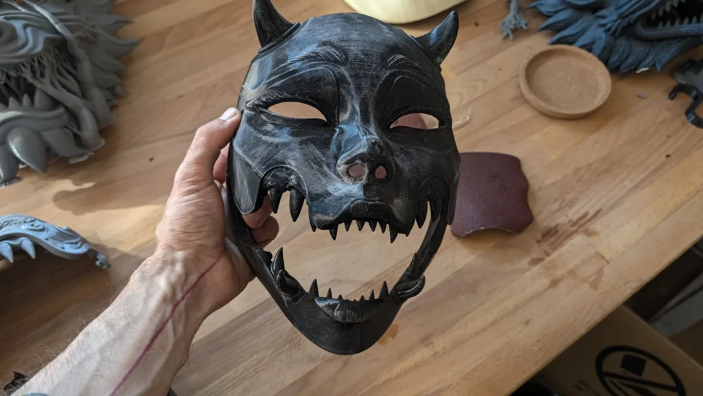 Máscara Kuchisake Onna lijada, sostenida en la mano con la mandíbula abierta en el taller Dai Yokai